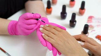 Manicurist treating client at beauty nails salon. Manicure, painting on nail